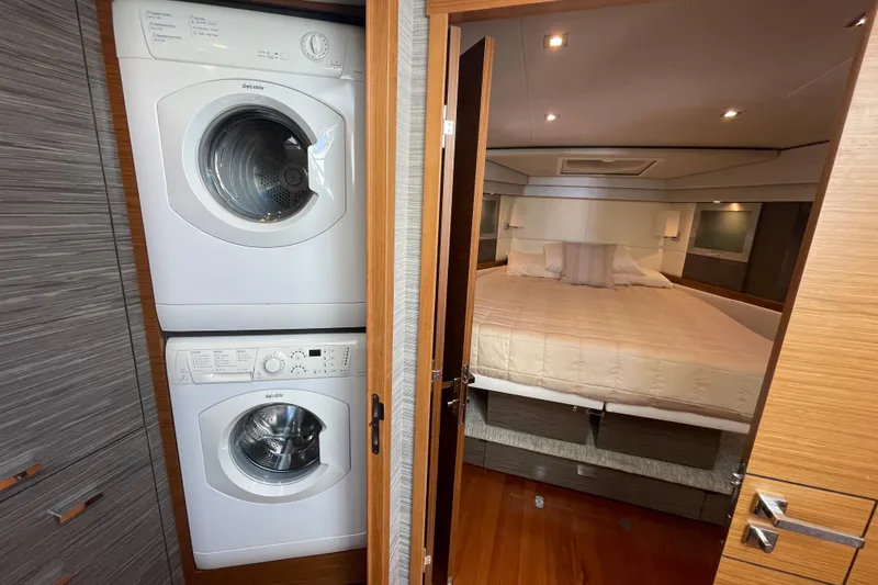 Slide: The Image of Stacked washer and dryer beside a cozy bedroom in a 2020 Tiara 53C yacht. - 28