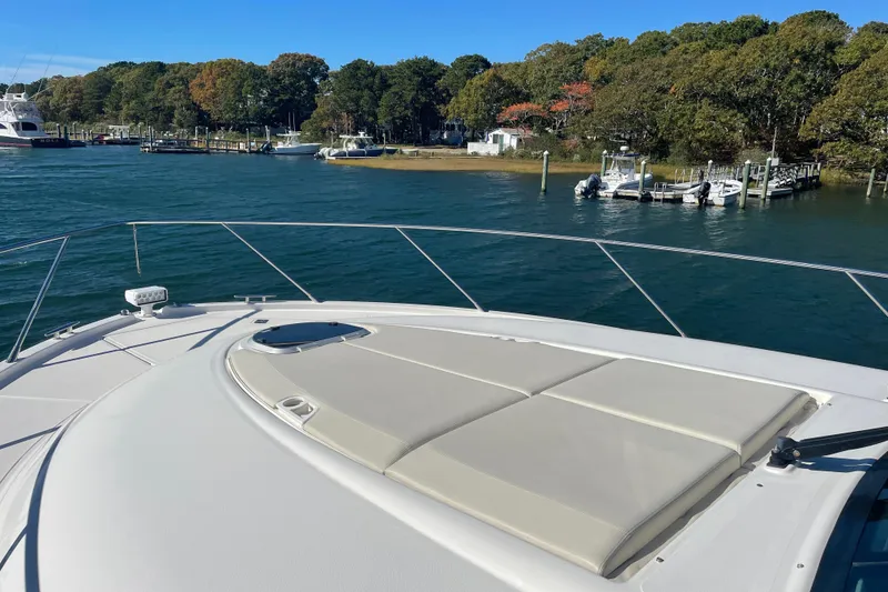 Slide: The Image of Luxurious 2020 Tiara 53C yacht with sunbathing deck, docked near scenic shoreline. - 4