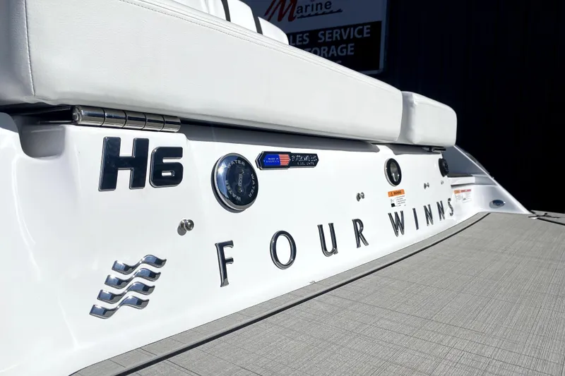Slide: The Image of 2026 Four Winns H6 boat, white exterior, close-up of branding and seating area. - 5
