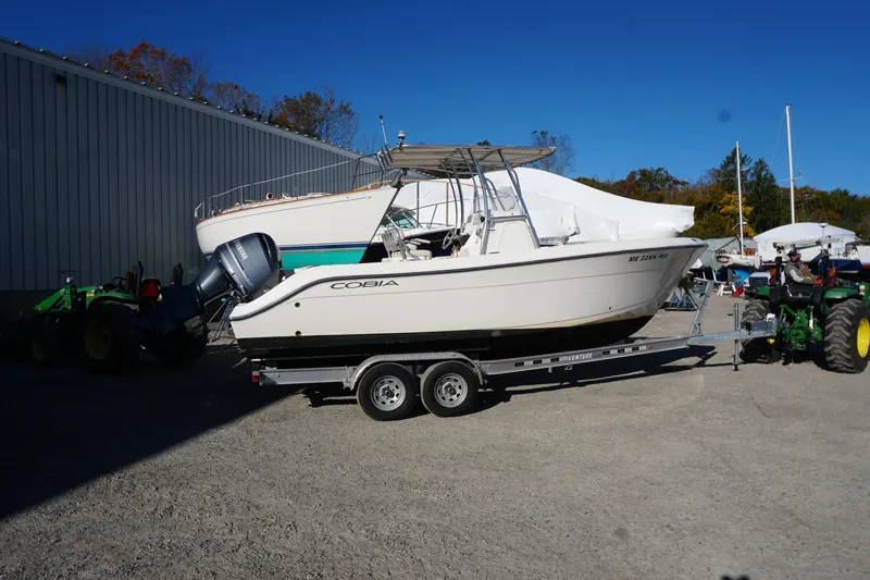 Slide: The Image of 2019 Cobia 237 Center Console boat on trailer, parked outdoors near a building. - 11