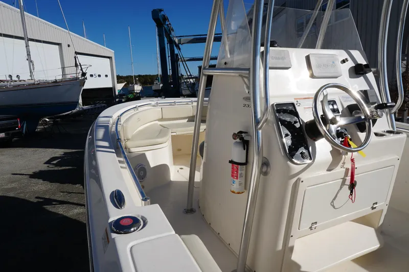 Slide: The Image of 2019 Cobia 237 Center Console boat with steering wheel and control panel in a marina. - 4