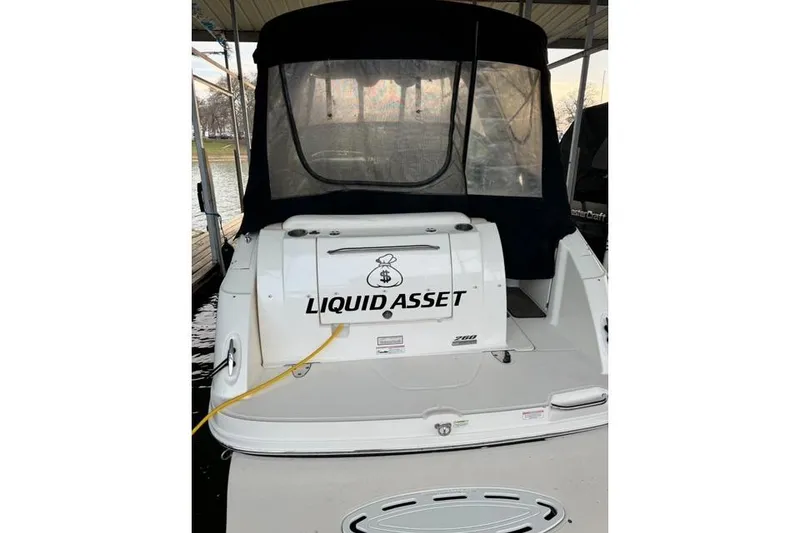 Slide: The Image of 2012 Sea Ray 260 Sundancer boat named "Liquid Asset" docked under a canopy. - 2