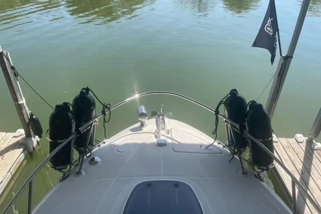 Slide: The Image of 2012 Sea Ray 260 Sundancer docked, bow view with calm water and black fenders. - 3