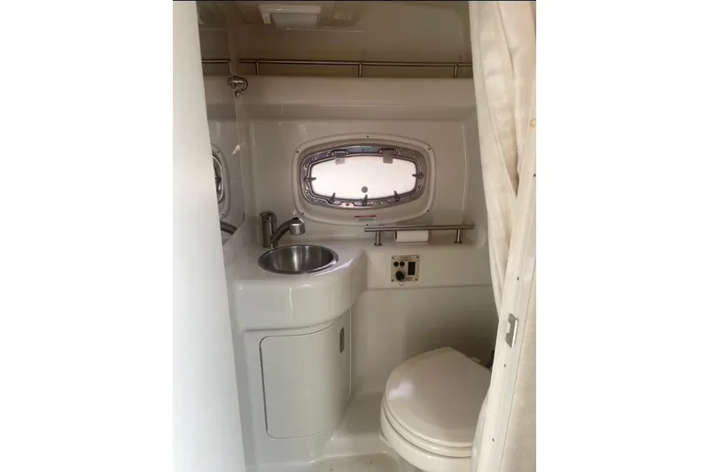 Slide: The Image of 2012 Sea Ray 260 Sundancer bathroom with sink, toilet, and porthole window. - 6
