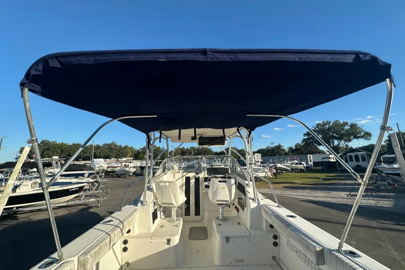 Slide: The Image of 2001 Boston Whaler 23 Conquest boat with canopy, docked under clear blue sky. - 18
