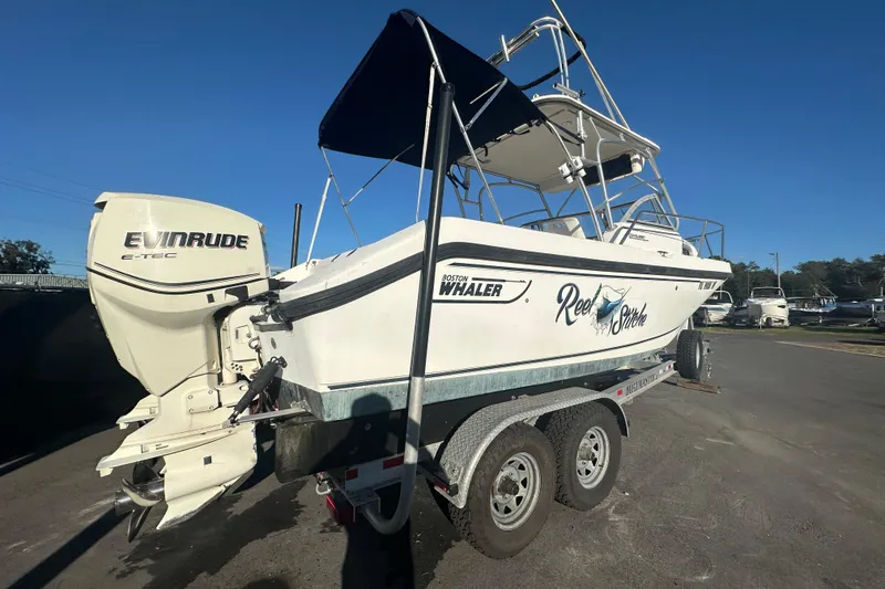 Slide: The Image of 2001 Boston Whaler 23 Conquest boat on trailer with Evinrude engine, sunny day. - 2