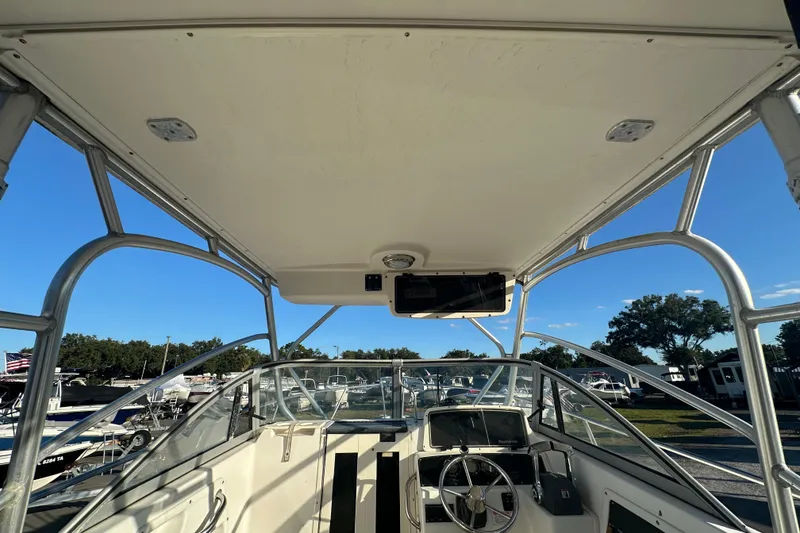 Slide: The Image of 2001 Boston Whaler 23 Conquest boat interior with steering wheel and canopy. - 24