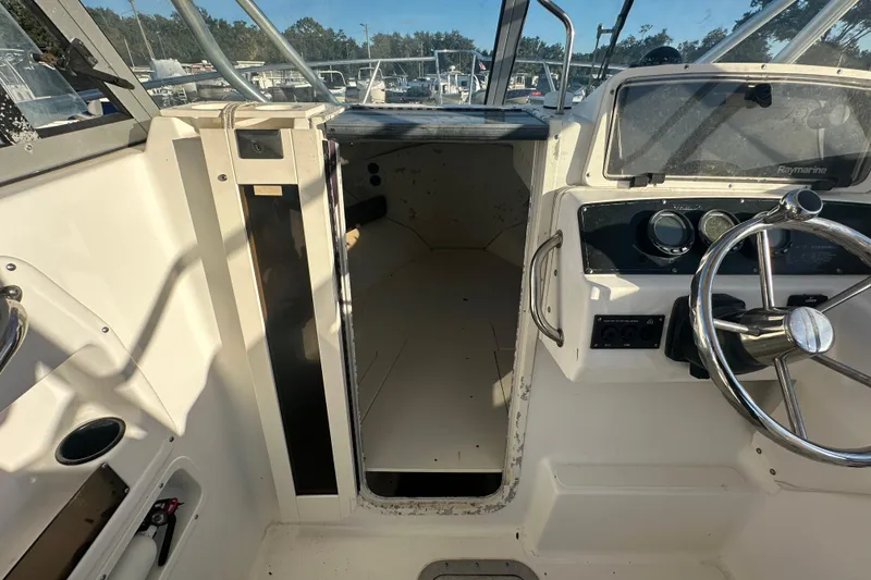 Slide: The Image of 2001 Boston Whaler 23 Conquest boat interior with steering wheel and cabin entrance. - 48