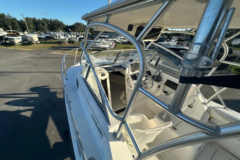 Slide: The Image of 2001 Boston Whaler 23 Conquest boat interior with steering wheel and seating, docked outdoors. - 57