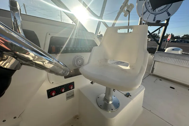 Slide: The Image of 2001 Boston Whaler 23 Conquest helm with steering wheel and captain's chair in sunlight. - 81