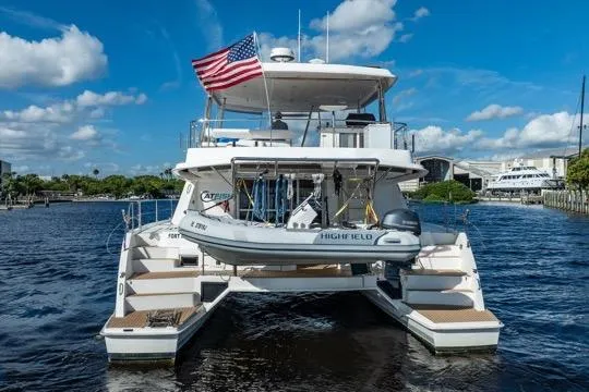 Slide: The Image of 2017 Leopard 51 Powercat yacht with dinghy, American flag, on calm water under blue sky. - 155