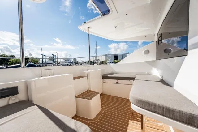Slide: The Image of 2017 Leopard 51 Powercat yacht interior with cushioned seating and wooden flooring under a clear sky. - 45