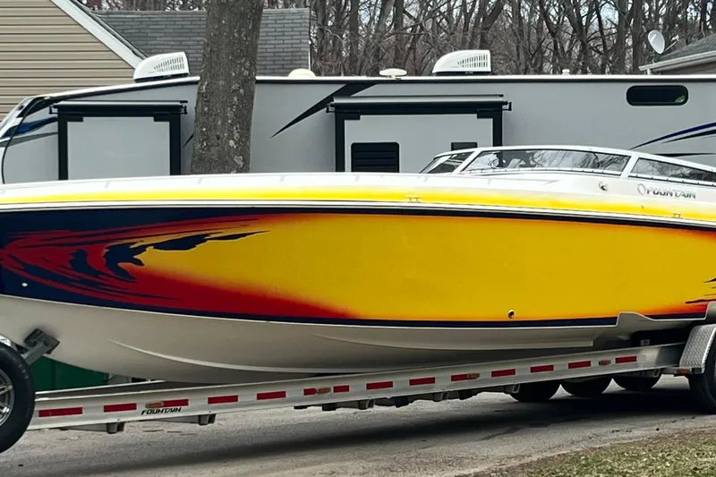 The Image of 2004 Fountain 42 Lightning speedboat with vibrant yellow and red design on a trailer. - 1