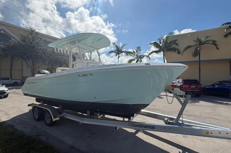The Image of 2021 Cobia 237 Center Console boat on trailer, parked outdoors under a sunny sky. - 0