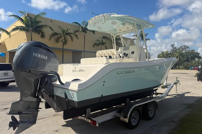 Slide: The Image of 2021 Cobia 237 Center Console boat on trailer with Yamaha engine, parked outdoors. - 2