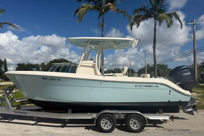 Slide: The Image of 2021 Cobia 237 Center Console boat on trailer, parked under palm trees. - 5