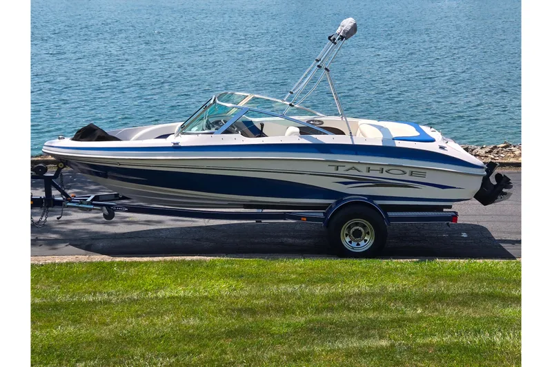 The Image of 2003 Tahoe Q5L boat on trailer by a lake, featuring sleek design and blue accents. - 0