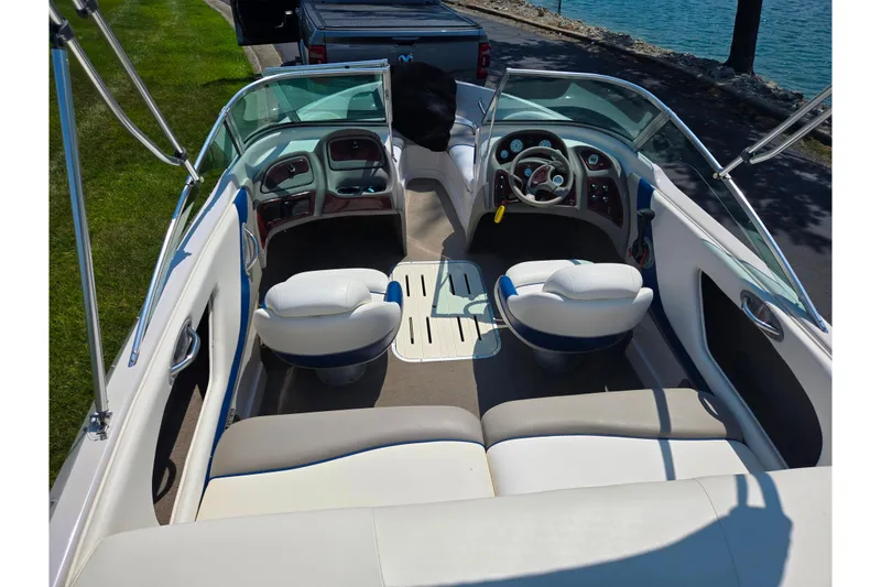 Slide: The Image of 2003 Tahoe Q5L boat interior with white seating and steering wheel, docked by a lake. - 10