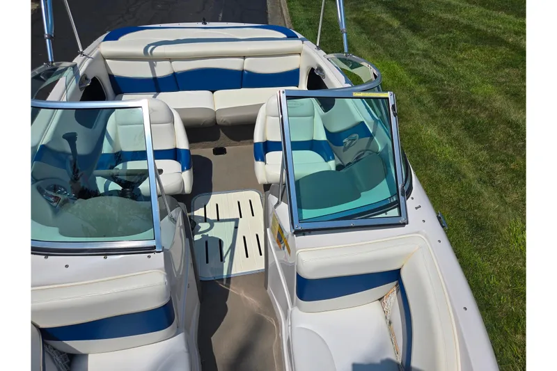 Slide: The Image of 2003 Tahoe Q5L boat interior with blue and white seating, open windshield, and grassy background. - 19