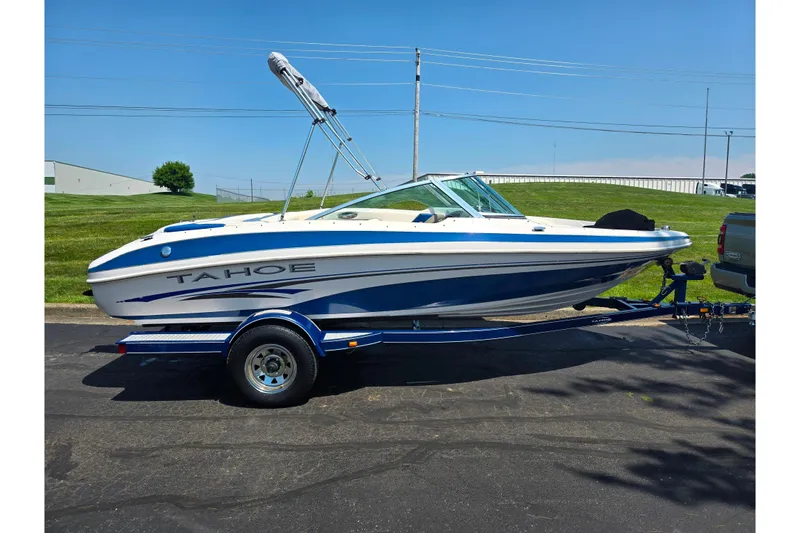 Slide: The Image of 2003 Tahoe Q5L boat on trailer, parked outdoors on a sunny day. - 4