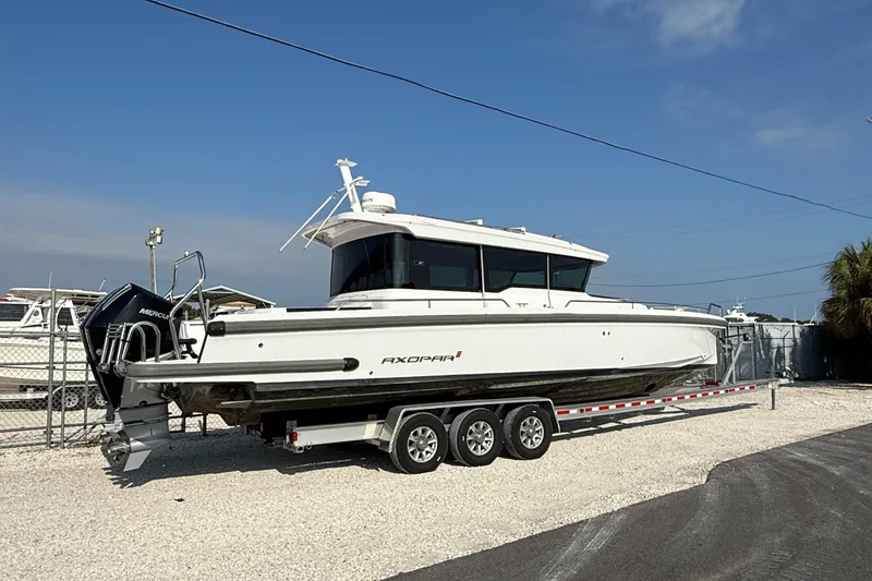 Slide: The Image of 2023 Axopar 37 XC CROSS CABIN boat on trailer, parked outdoors. - 2