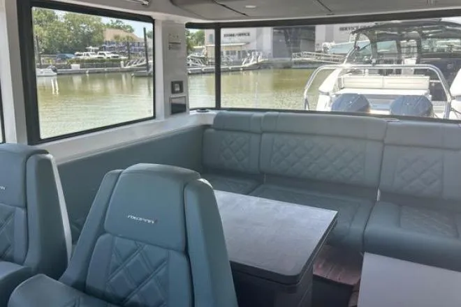 Slide: The Image of Interior of 2023 Axopar 37 XC CROSS CABIN with seating and table, docked by water. - 24