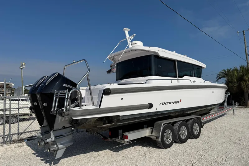 Slide: The Image of 2023 Axopar 37 XC CROSS CABIN boat on trailer, featuring dual Mercury engines. - 5