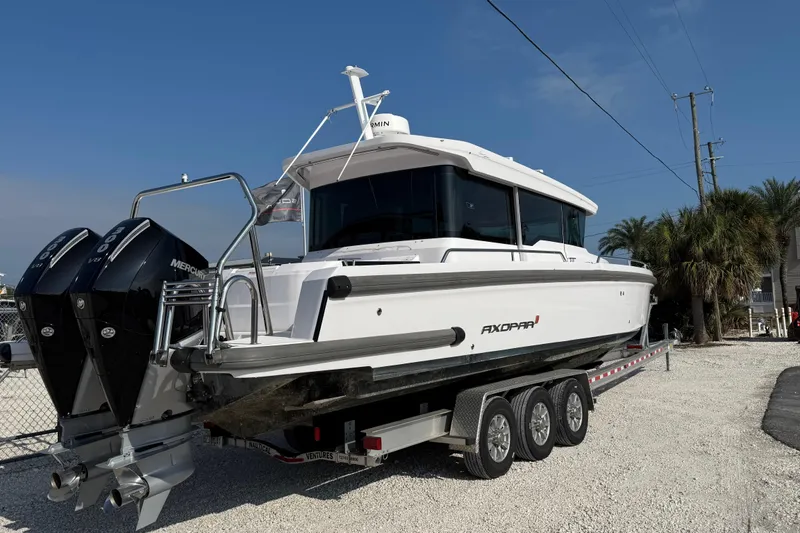 Slide: The Image of 2023 Axopar 37 XC CROSS CABIN boat on trailer, featuring twin Mercury engines. - 6