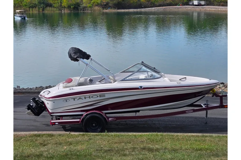 The Image of 2011 Tahoe Q4 SS boat on trailer by a serene lake. - 0