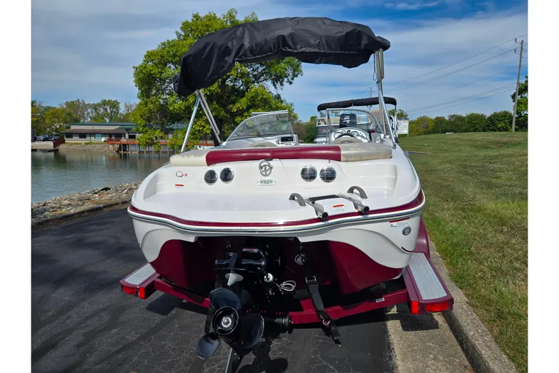 Slide: The Image of 2011 Tahoe Q4 SS boat with canopy, parked near a lake on a sunny day. - 2