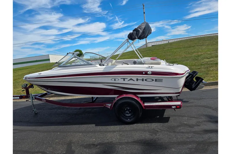 Slide: The Image of 2011 Tahoe Q4 SS boat on trailer, parked outdoors under a blue sky. - 4