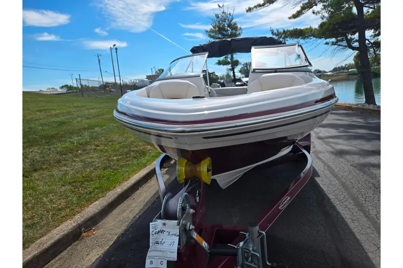 Slide: The Image of 2011 Tahoe Q4 SS boat on trailer, parked near a lake under a clear blue sky. - 6