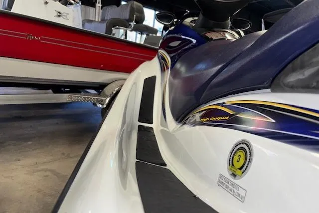 Slide: The Image of 2004 Yamaha WaveRunner FX jet ski, white and blue, parked indoors near a red boat. - 10