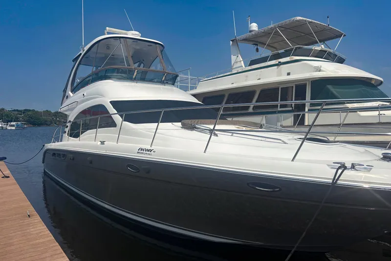 The Image of 2006 Sea Ray 52 Sedan Bridge yacht docked at marina under clear blue sky. - 0