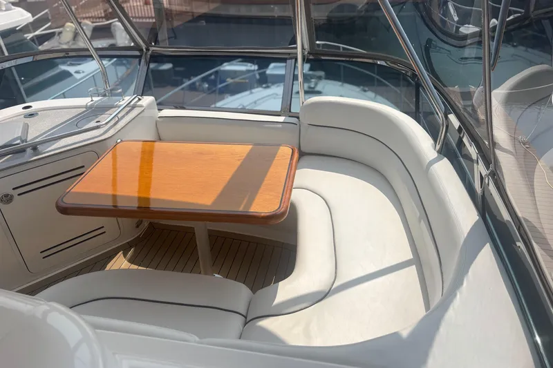 Slide: The Image of 2006 Sea Ray 52 Sedan Bridge interior with curved seating and wooden table. - 11