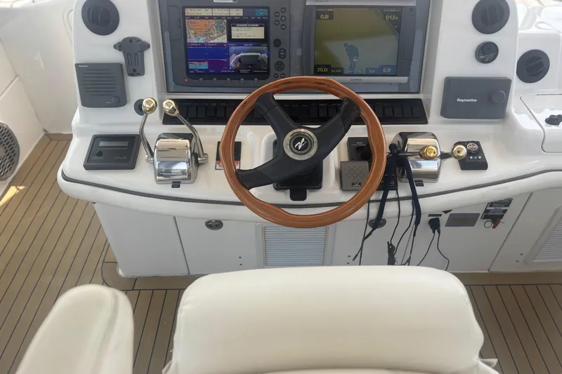 Slide: The Image of 2006 Sea Ray 52 Sedan Bridge helm with navigation screens and wooden steering wheel. - 13