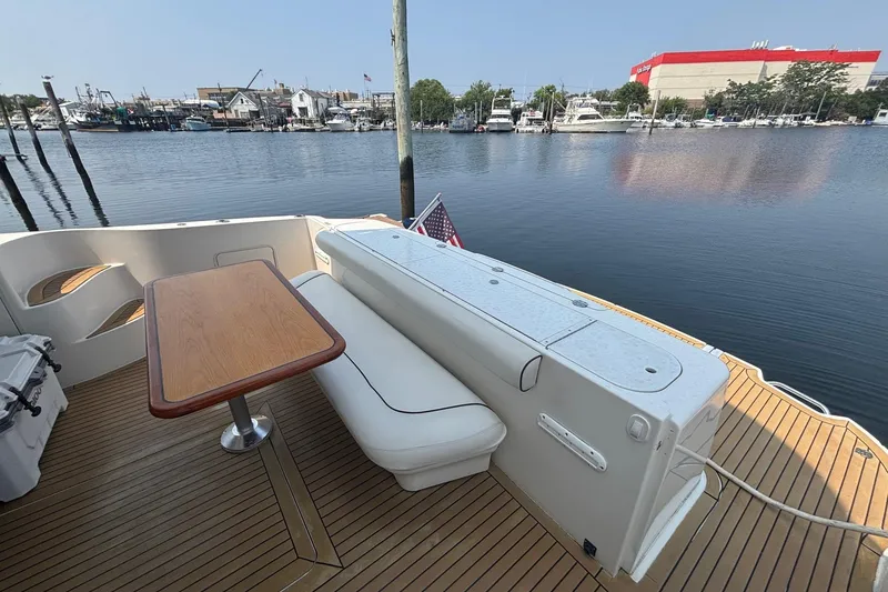 Slide: The Image of 2006 Sea Ray 52 Sedan Bridge yacht deck with seating and table, docked at marina. - 21