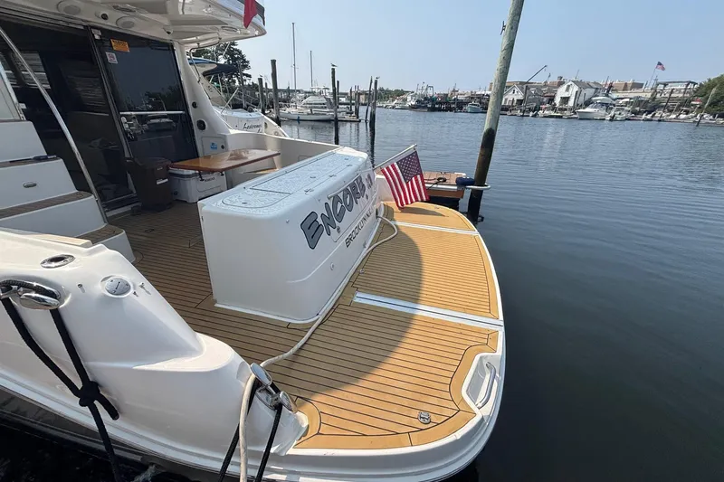 Slide: The Image of 2006 Sea Ray 52 Sedan Bridge yacht docked, featuring teak deck and American flag. - 23
