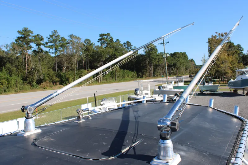 Slide: The Image of Rooftop view of 2020 AMERICAT 27cc boat with fishing outriggers, surrounded by trees and road. - 11