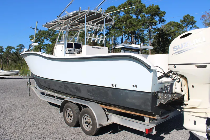 Slide: The Image of 2020 AMERICAT 27cc boat on trailer with Suzuki outboard motor, parked outdoors. - 28