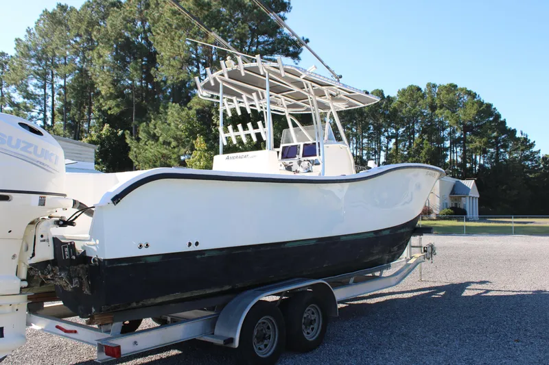 Slide: The Image of 2020 AMERICAT 27cc boat on trailer with Suzuki engine, surrounded by trees. - 6