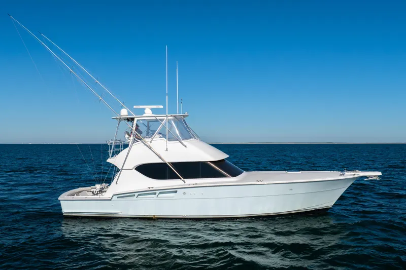 The Image of 2000 Hatteras 50 Convertible yacht on open sea under clear blue sky. - 0