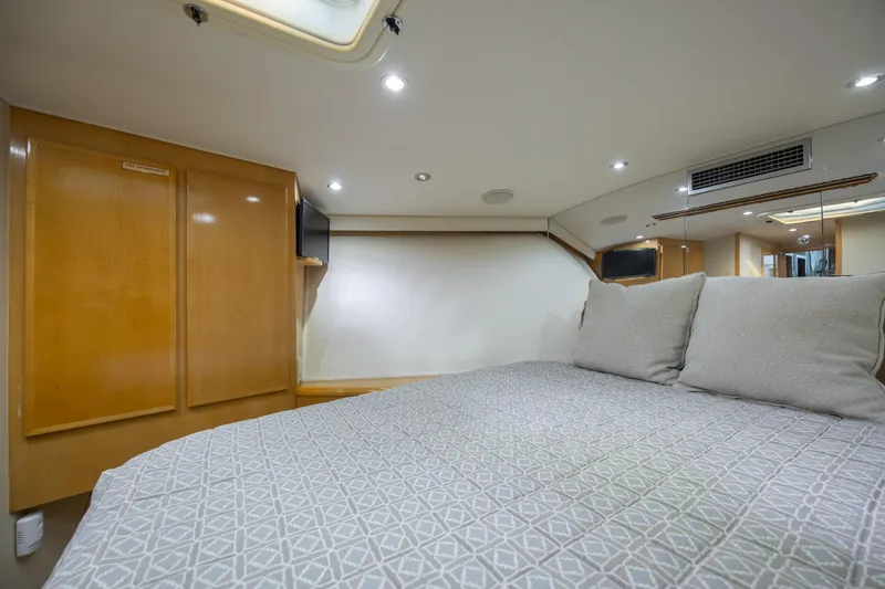 Slide: The Image of Interior of 2000 Hatteras 50 Convertible yacht, featuring a cozy bedroom with modern amenities. - 60
