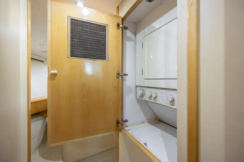 Slide: The Image of Laundry area inside 2000 Hatteras 50 Convertible yacht, featuring a compact washer and dryer. - 66