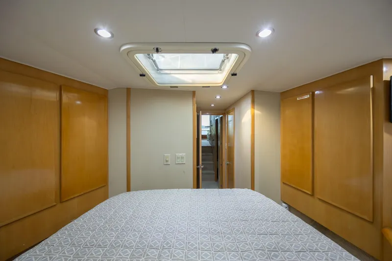 Slide: The Image of Interior of 2000 Hatteras 50 Convertible yacht, featuring a cozy bedroom with wood paneling. - 71
