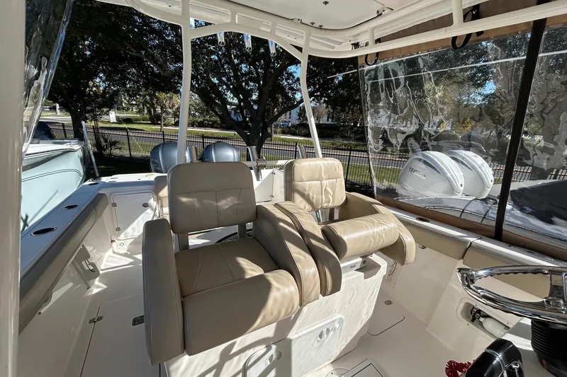 Slide: The Image of 2015 Pursuit C 280 Center Console boat interior with beige seating and steering wheel. - 10