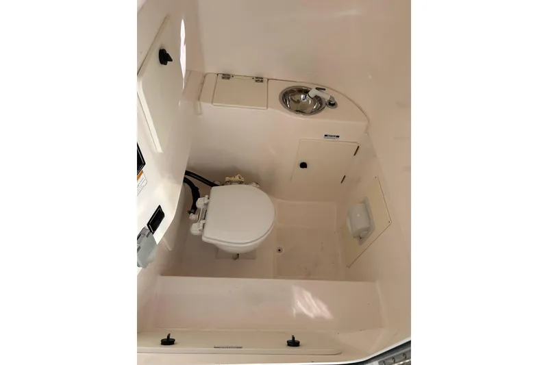 Slide: The Image of 2015 Pursuit C 280 Center Console boat interior with toilet and sink. - 8