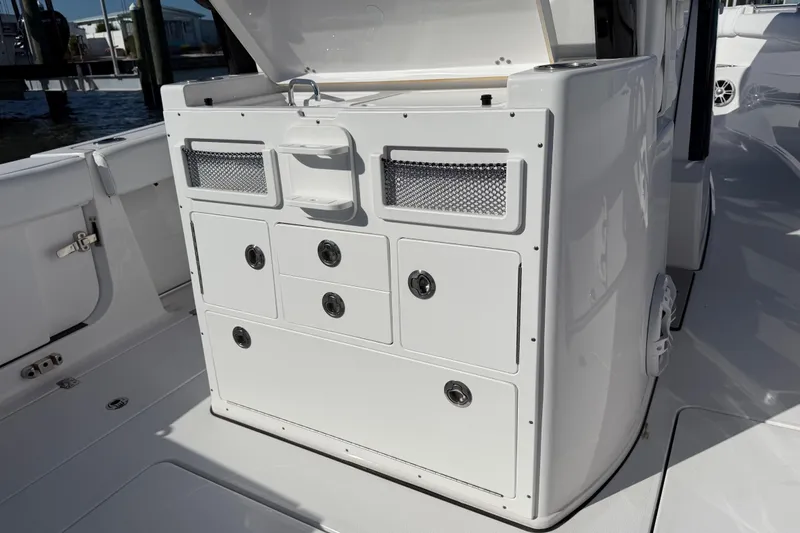 Slide: The Image of 2024 Sportsman Open 282TE Center Console storage compartment with open lid, showcasing drawers and mesh pockets. - 23