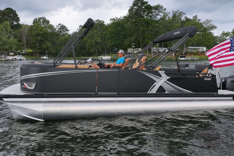 Slide: The Image of 2026 Avalon LSZ Quad Lounger Shift pontoon boat on a lake with American flag. - 6