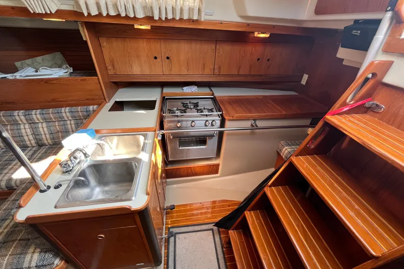 Slide: The Image of Interior of a 1984 C&C 41 sailboat featuring a compact kitchen with stove and sink. - 42